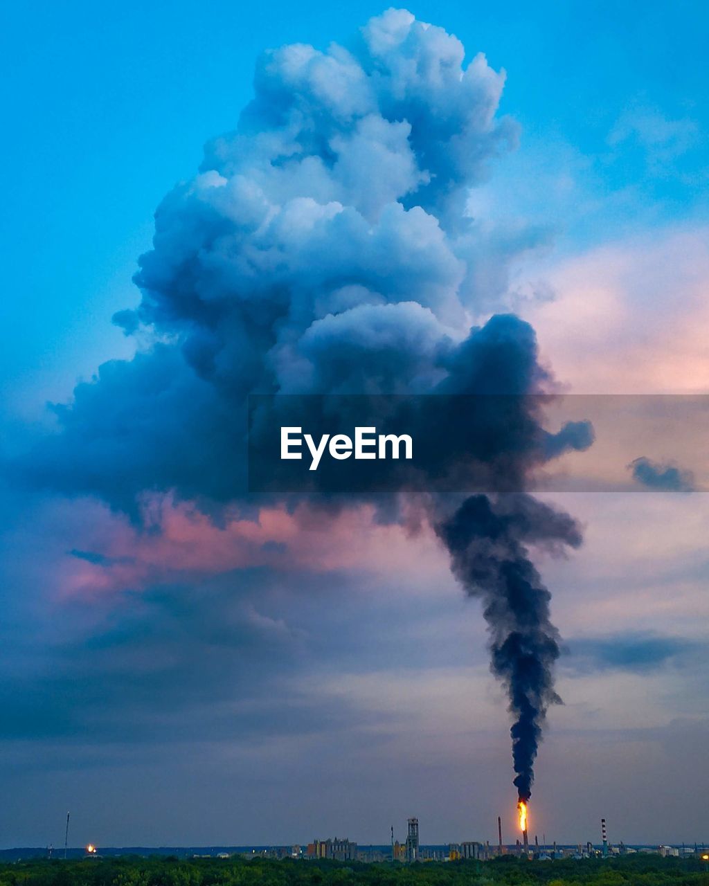 Smoke emitting from chimney against cloudy sky