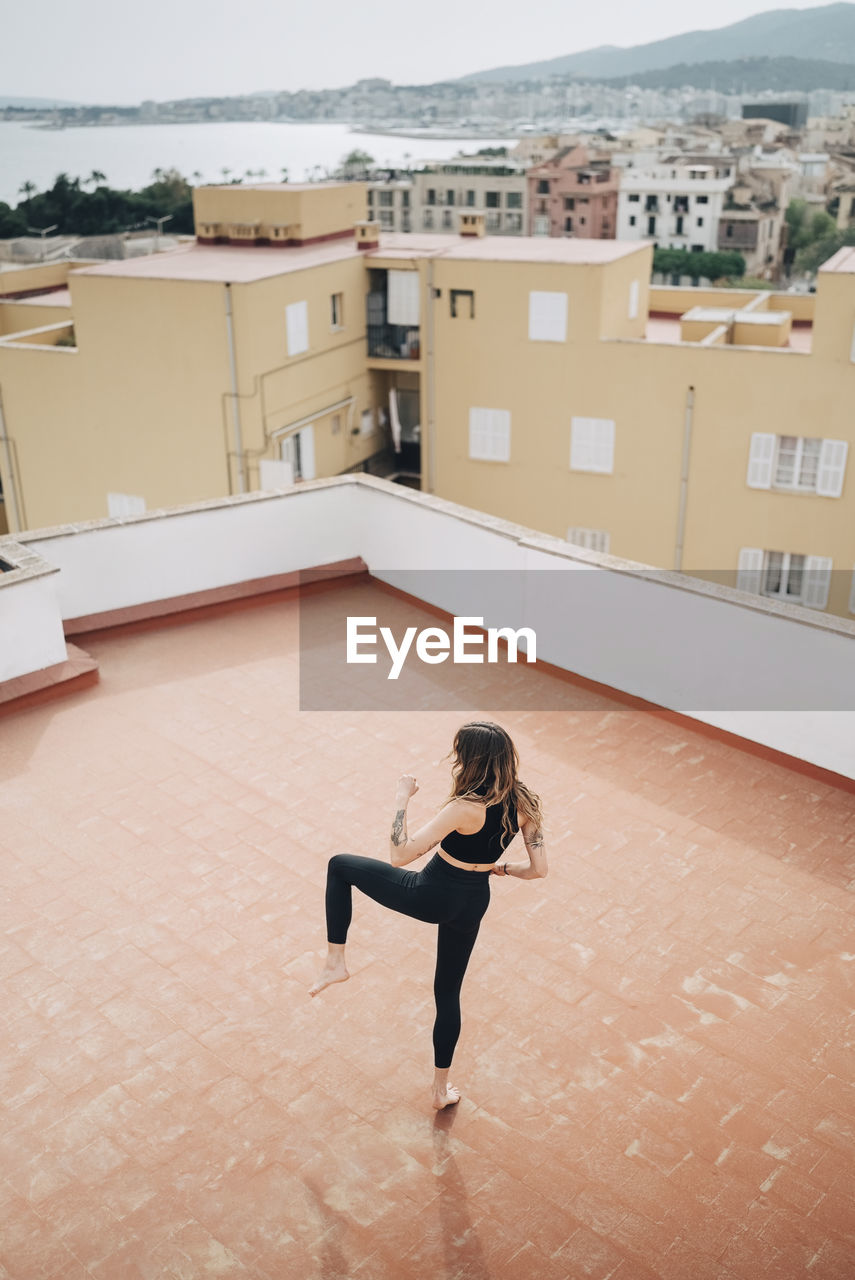 High angle view of woman practicing kicks on building terrace