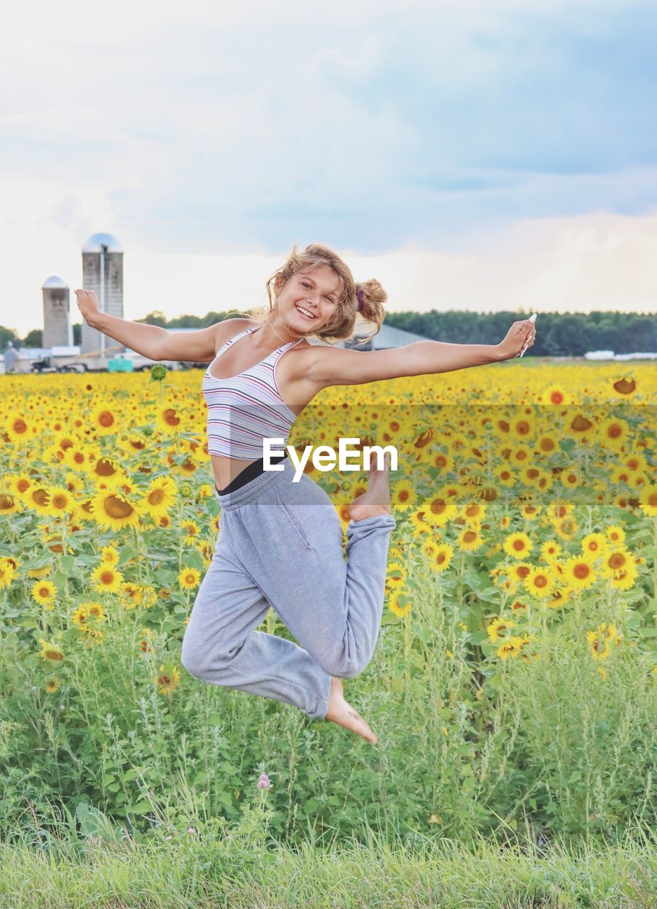 Young lady jumping in a field of sunflowers