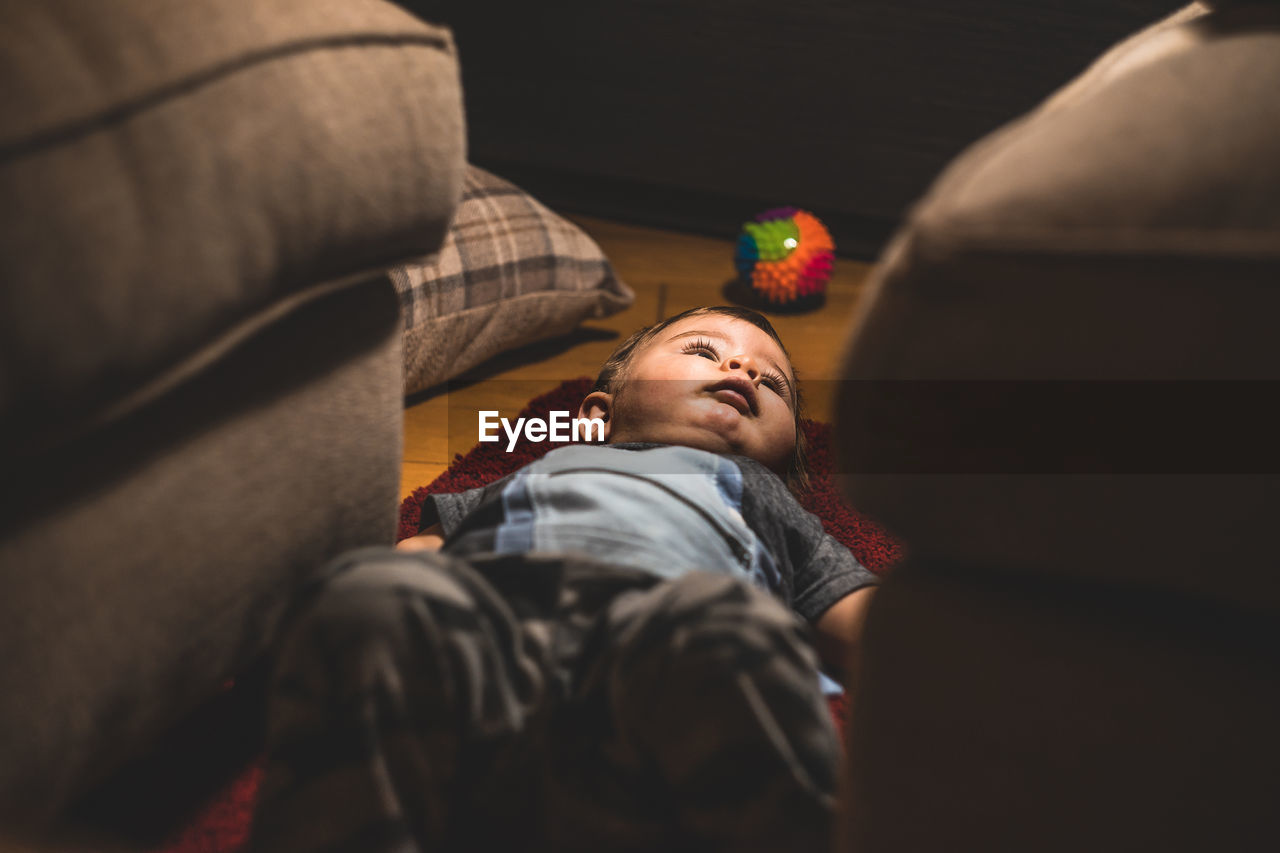 Cute boy lying down on carpet at home