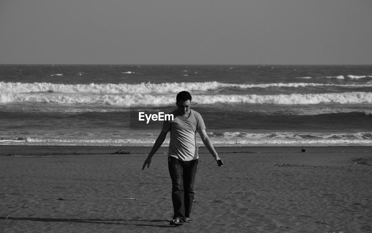 Man standing on sand against sea