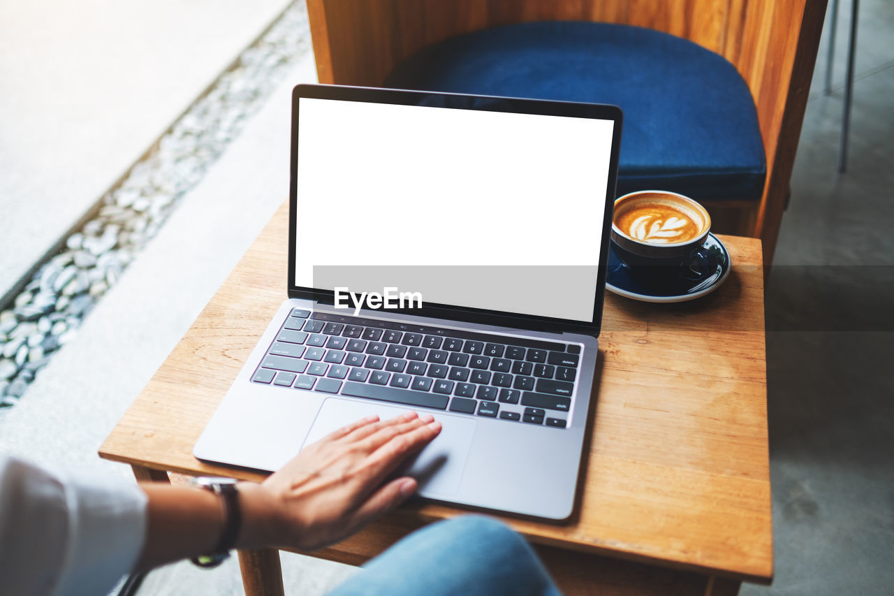 cropped hands of man using laptop on table