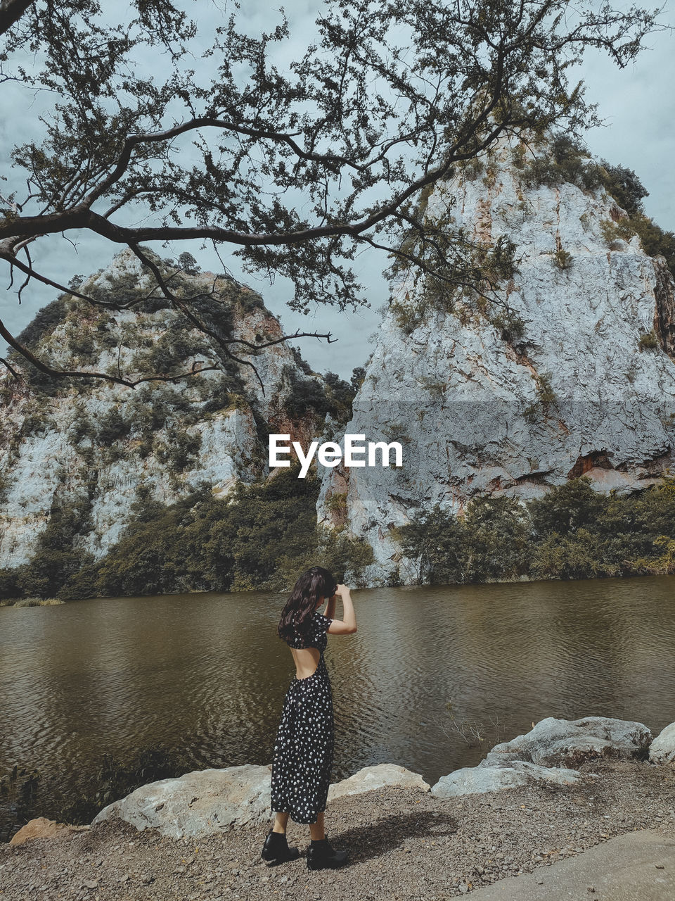 Portrait of woman in sexy back dress standing in front of rock mountain lakes 