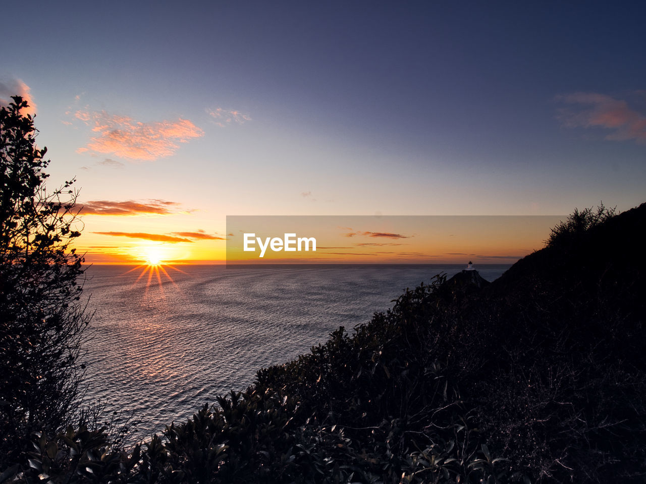 sky, sunset, water, sea, beauty in nature, scenics - nature, nature, cloud, land, tranquility, horizon, dawn, tranquil scene, beach, plant, environment, landscape, sun, evening, tree, no people, sunlight, coast, silhouette, horizon over water, idyllic, outdoors, dramatic sky, orange color, afterglow, ocean, travel destinations, seascape, non-urban scene, travel, coastline
