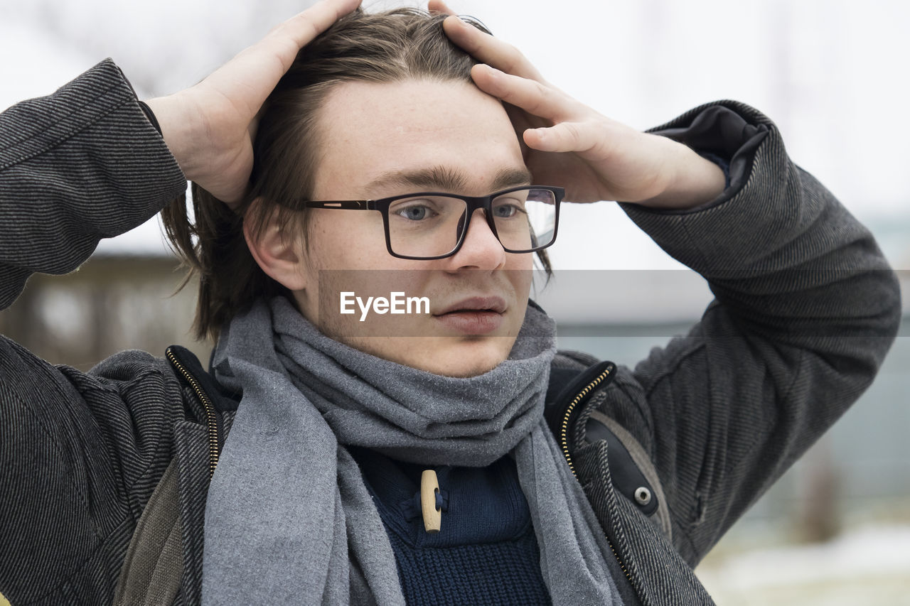 Thoughtful young man wearing warm clothing looking away