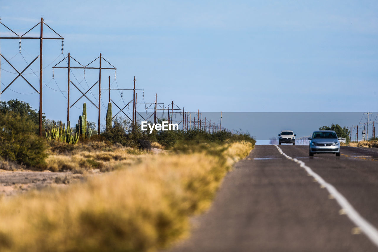 CAR ON ROAD BY LAND AGAINST SKY