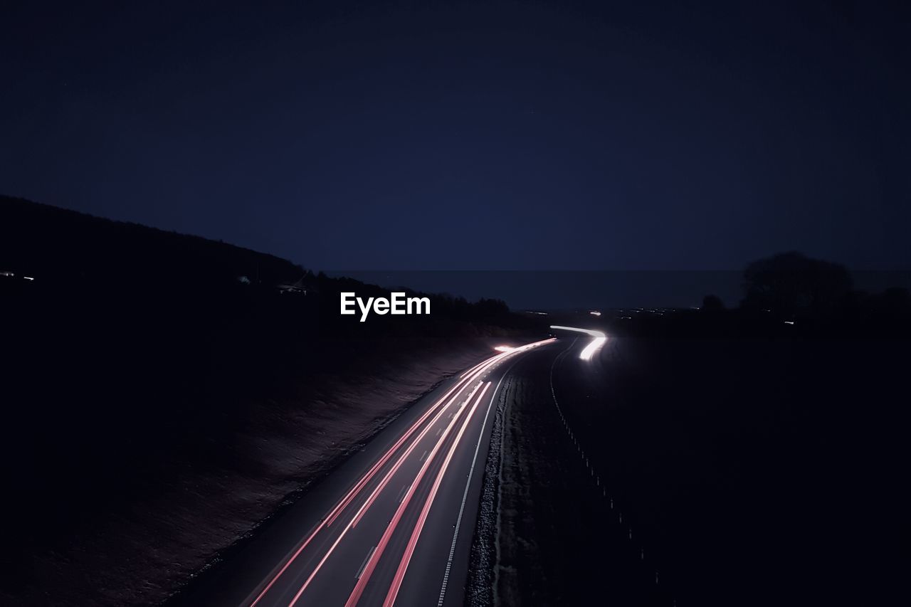 Light trails on road against sky at night