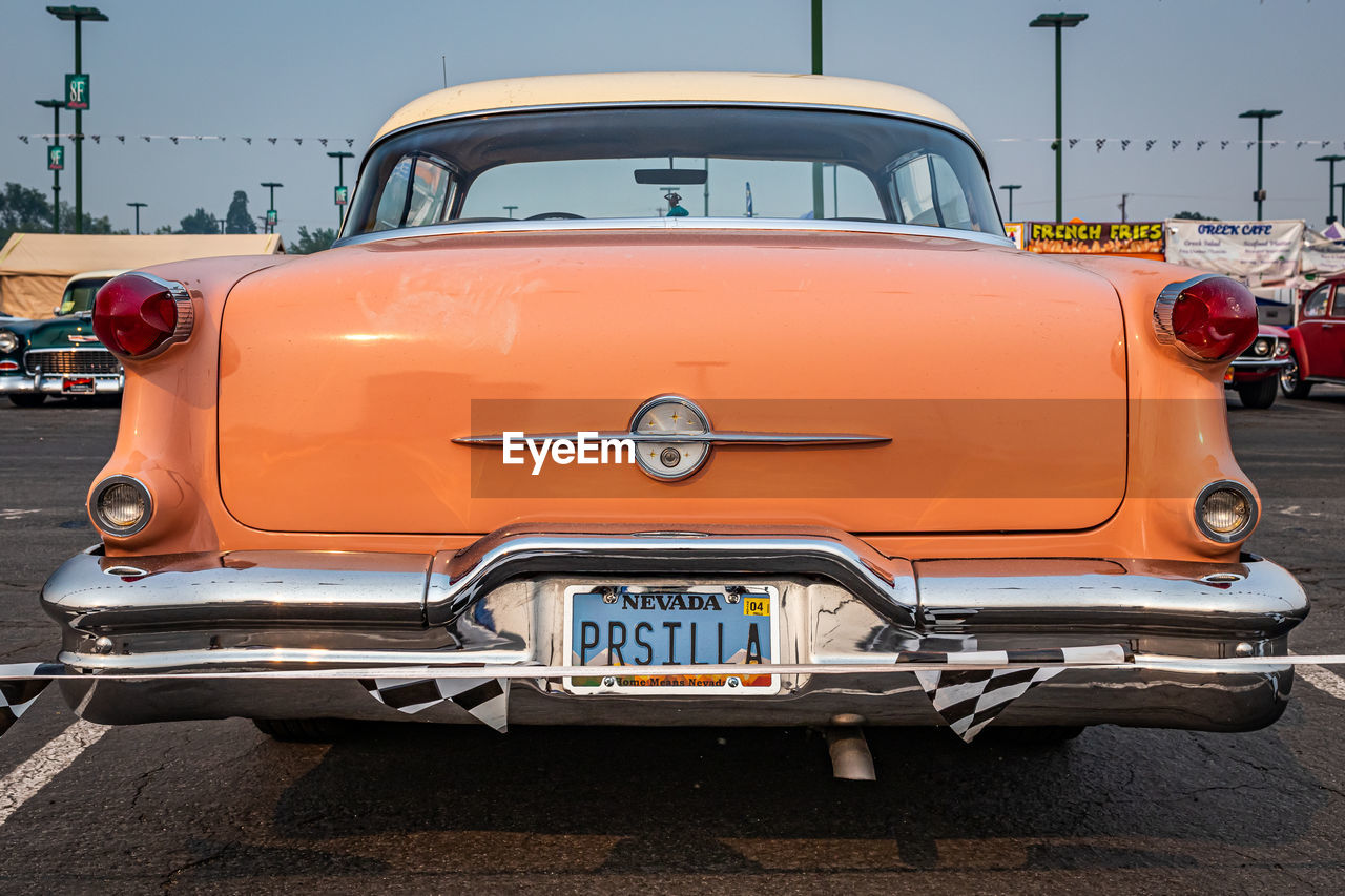 car, vehicle, mode of transportation, transportation, land vehicle, motor vehicle, antique car, street, city, automotive exterior, luxury vehicle, architecture, vintage car, orange color, road, taxi, retro styled, automobile, sky, travel, traffic, no people, outdoors, hot rod