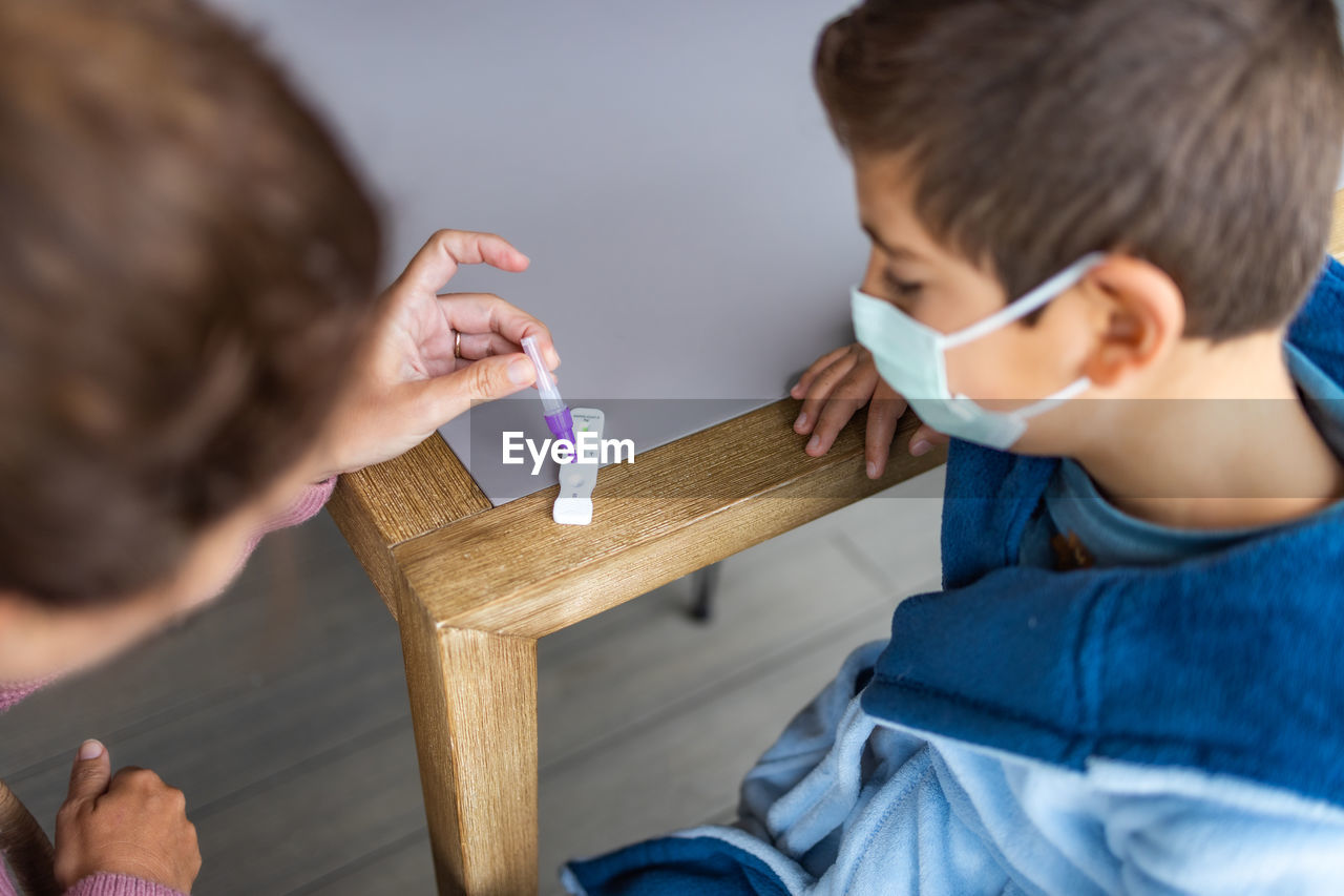 Mother doing an antigen test to her son at home