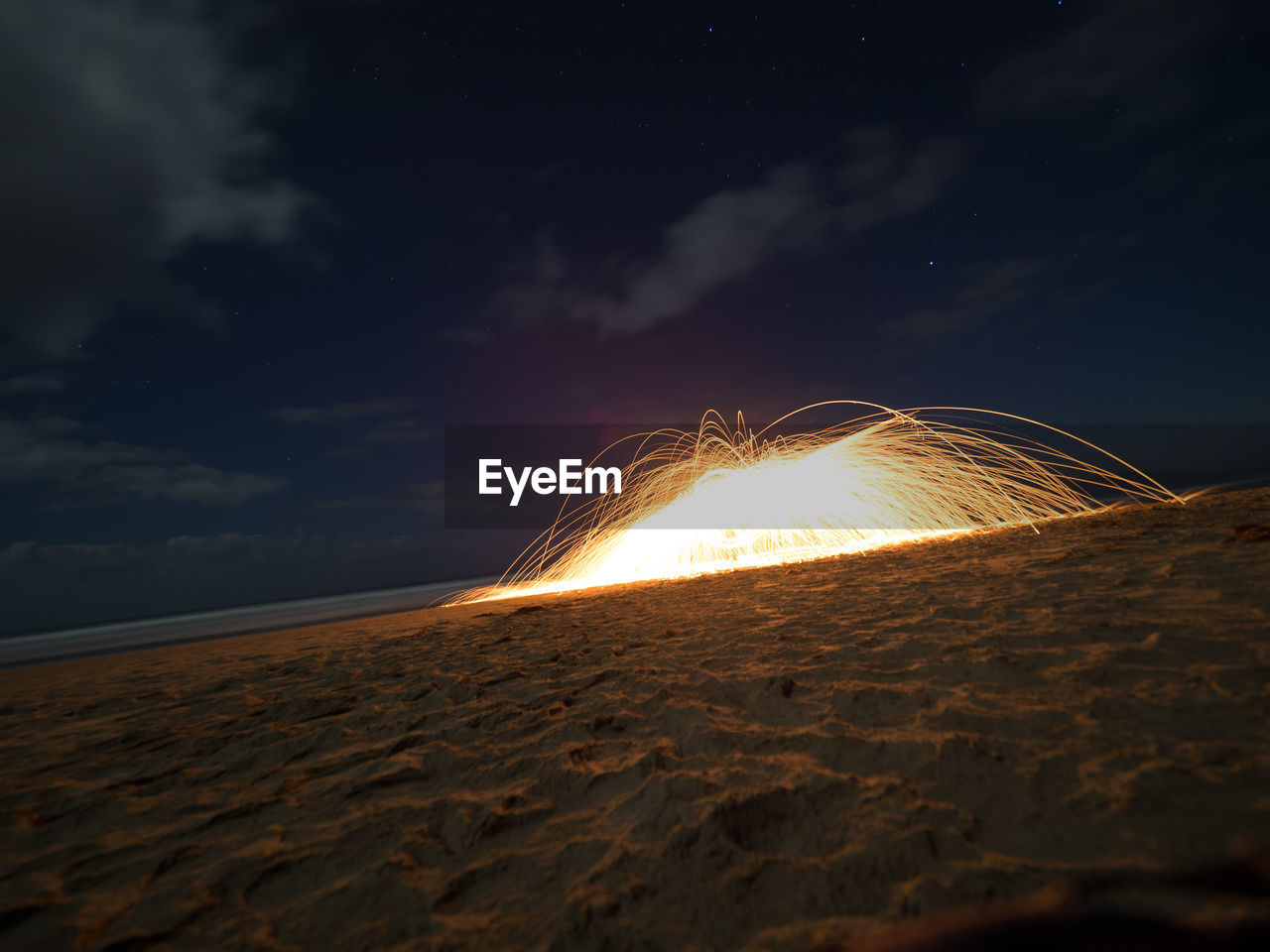 Wire wool at beach against sky at night