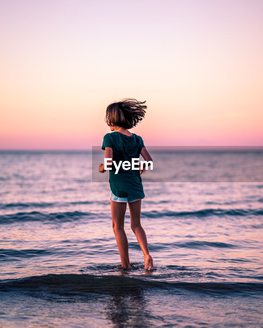 Young woman standing against sea during sunset