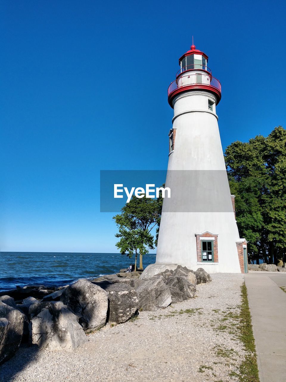 Lighthouse by sea against clear sky