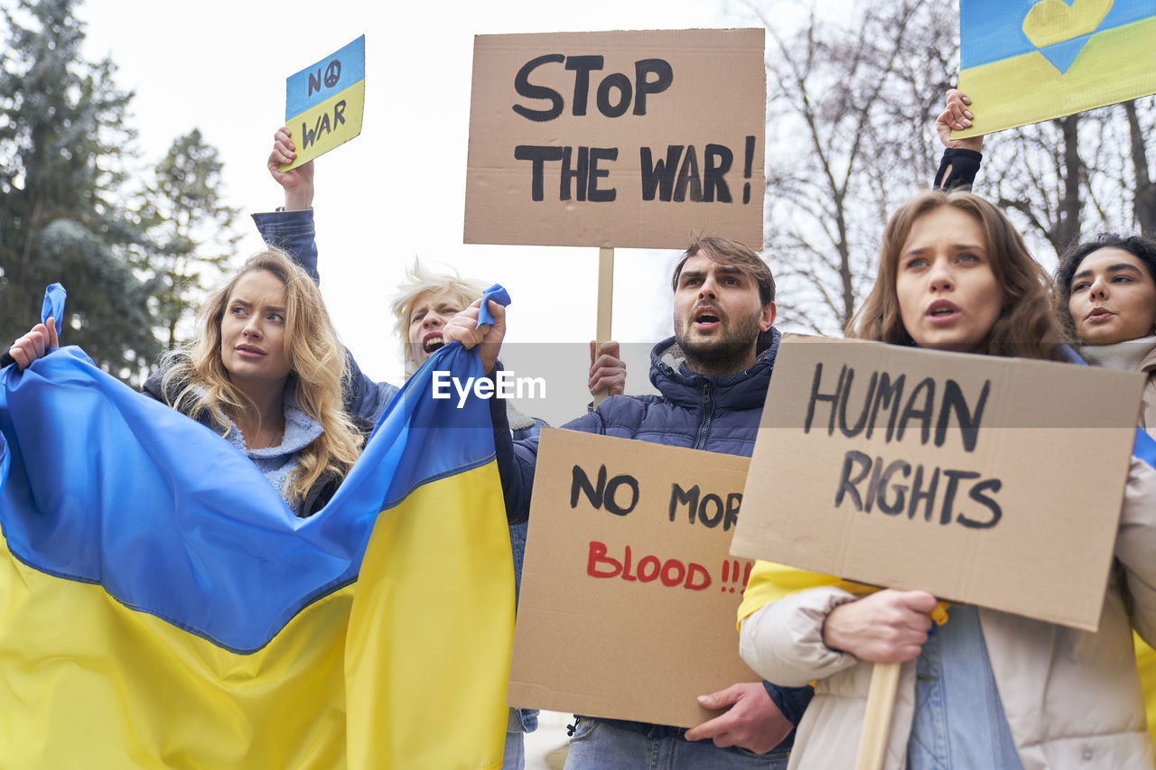 Low angle view of people protesting against sky