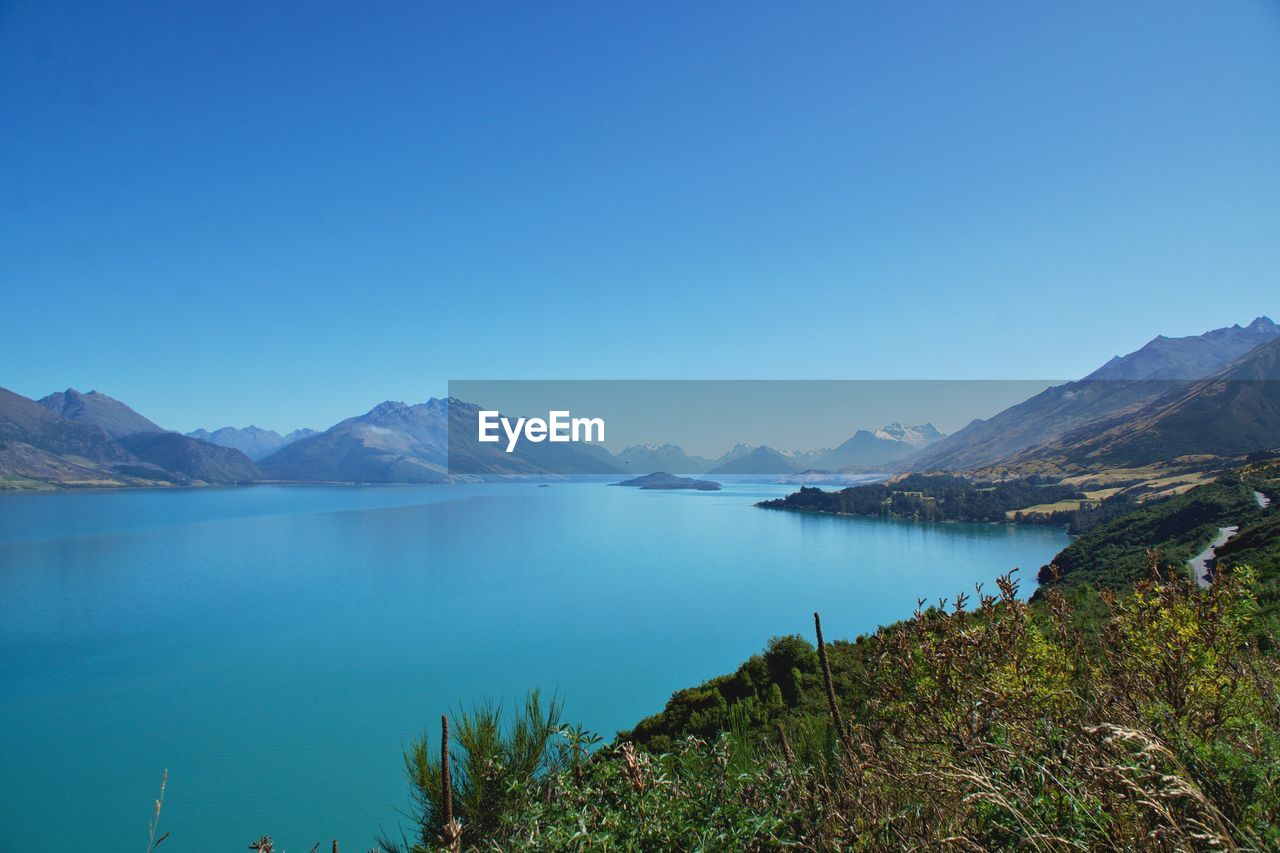 SCENIC VIEW OF LAKE AND MOUNTAINS AGAINST BLUE SKY