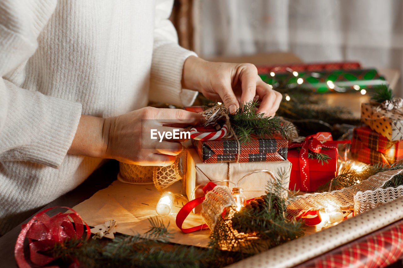 Women's hands decorate the box with the christmas gift. table with decor and materials for