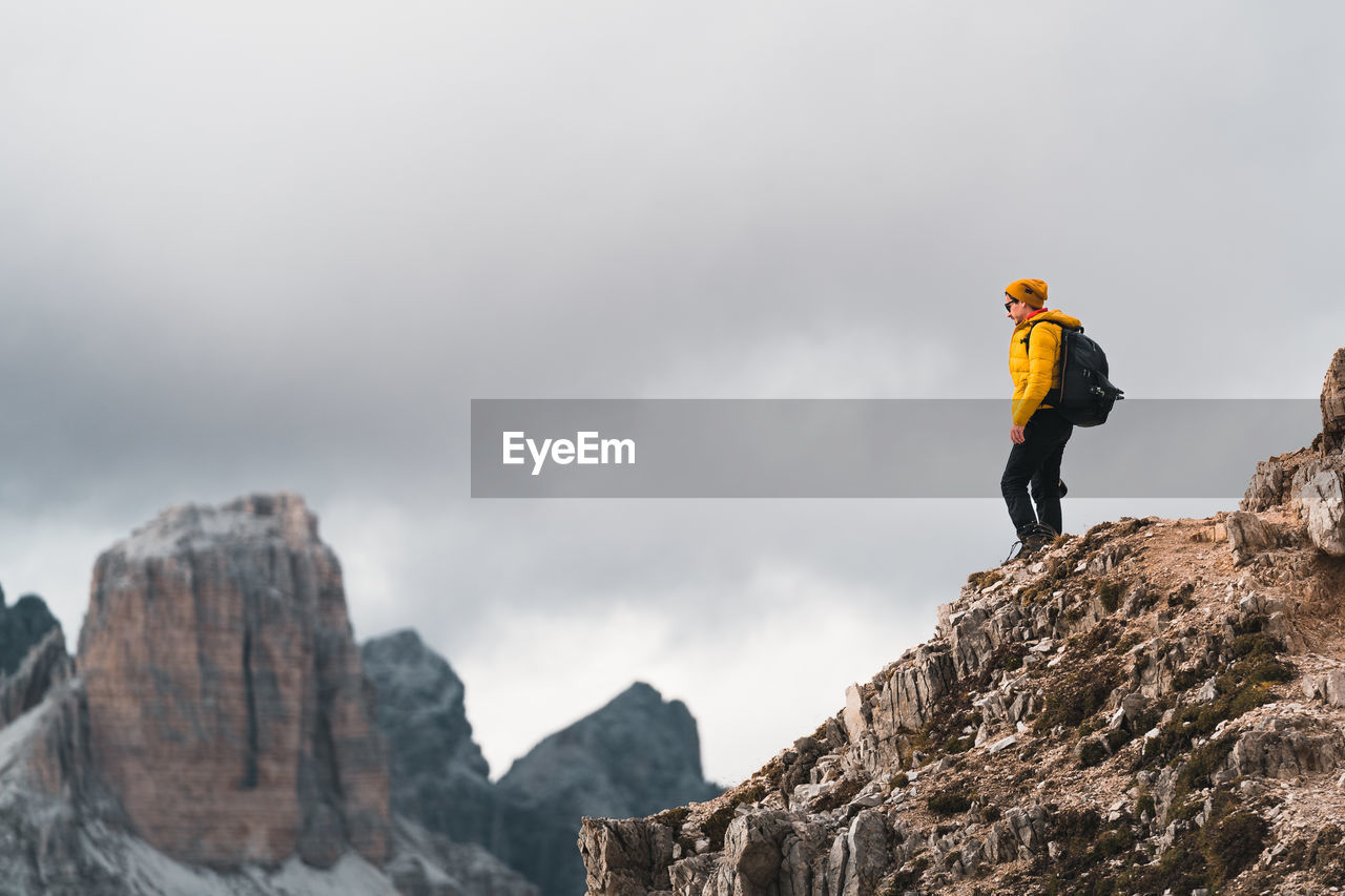 low angle view of man standing on rock against sky