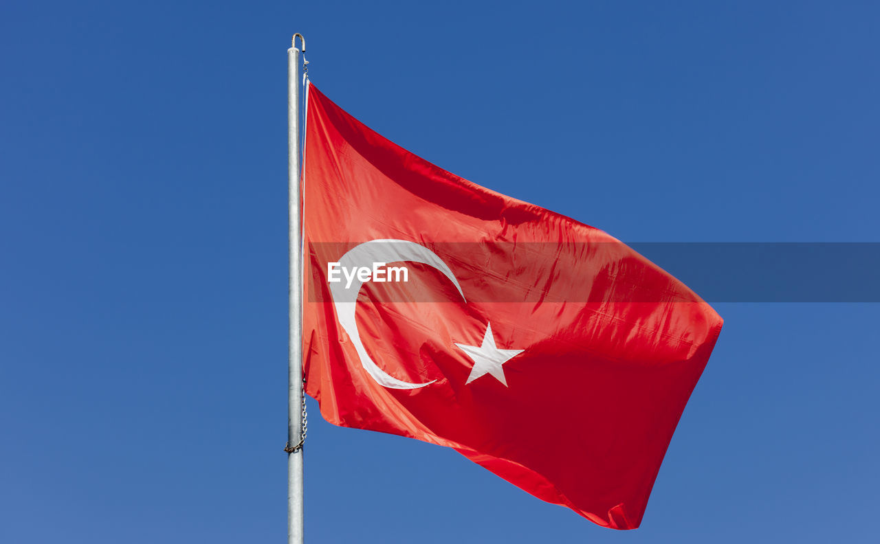 Low angle view of turkish flag against clear blue sky