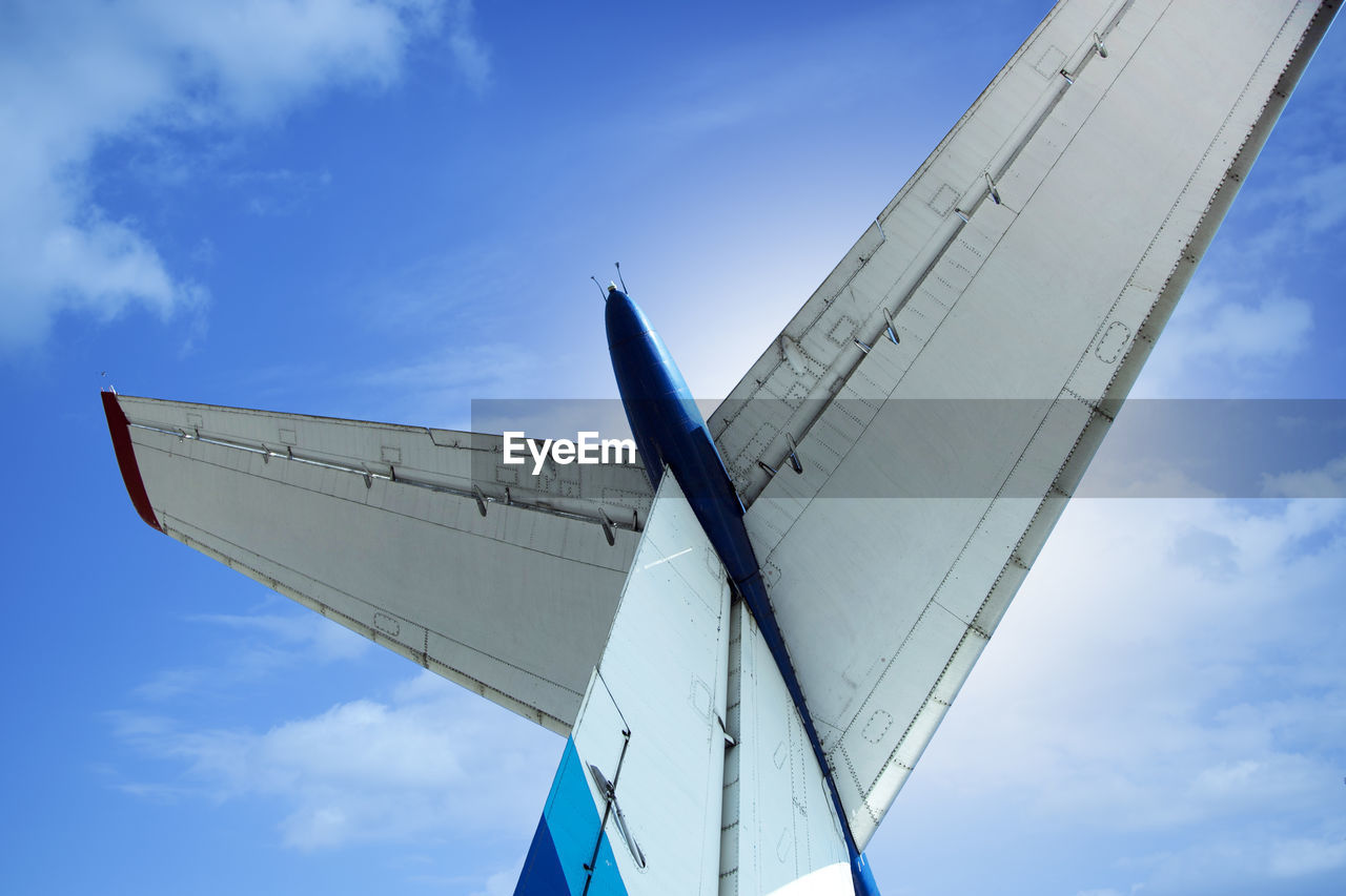 Low angle view of airplane wing against blue sky