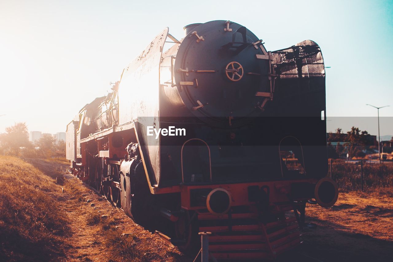 Steam train on field against sky