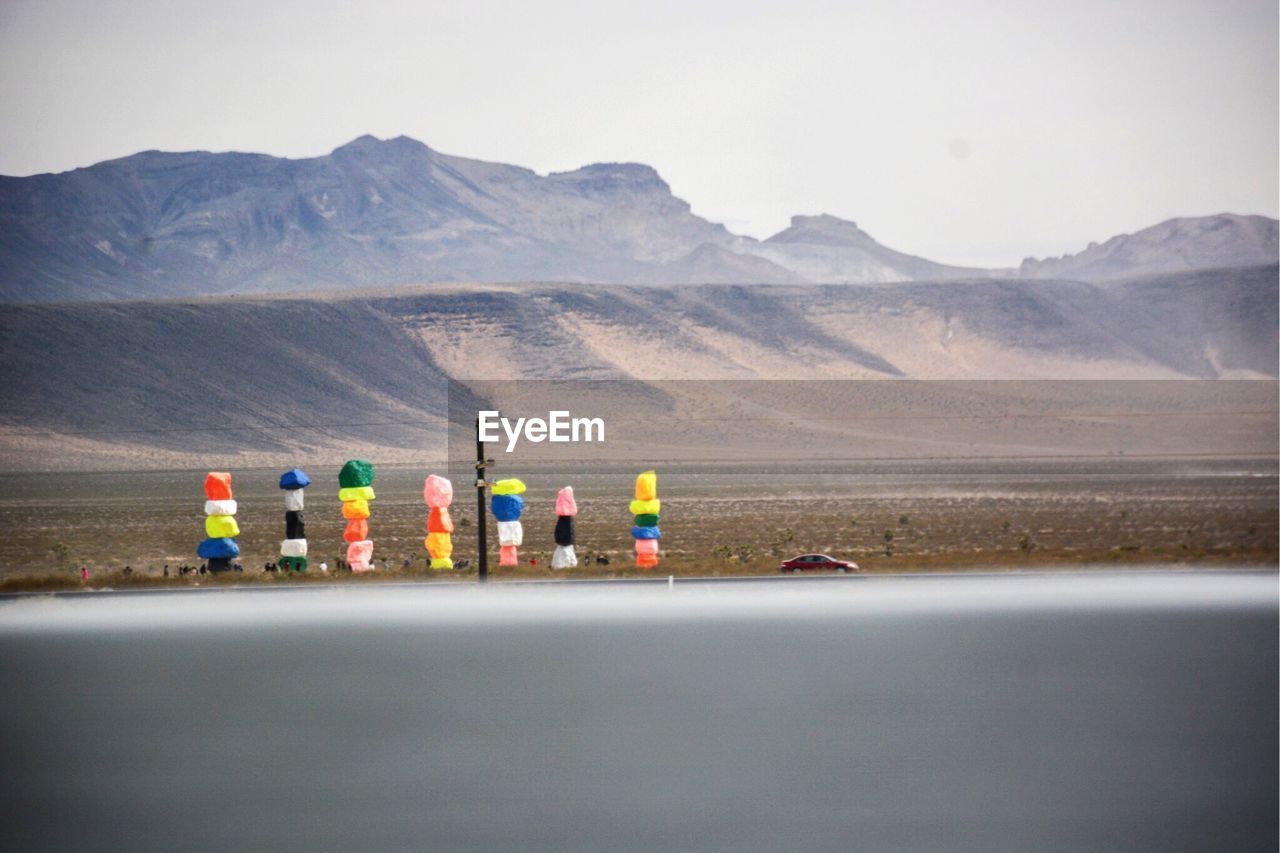 Stack of colorful rocks on roadside against mountains