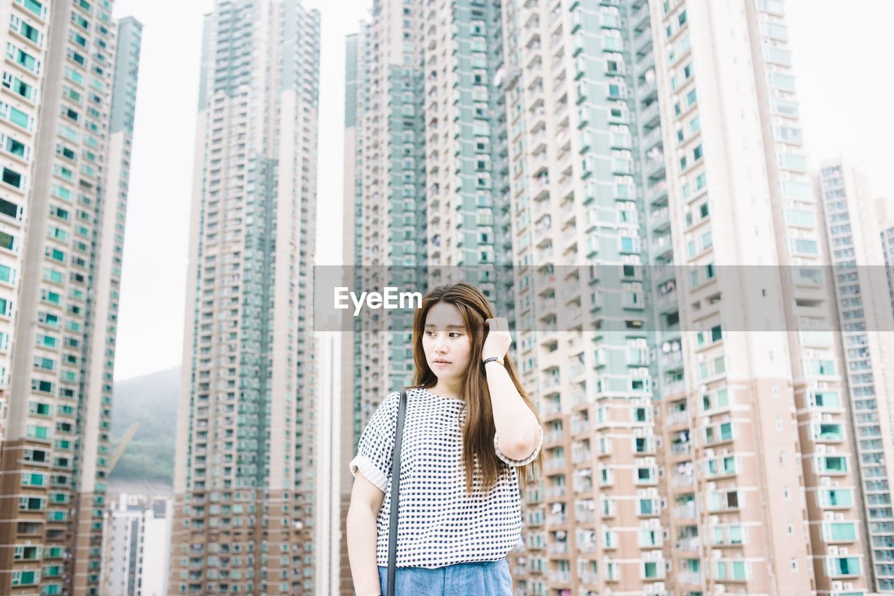 Beautiful woman standing against modern buildings