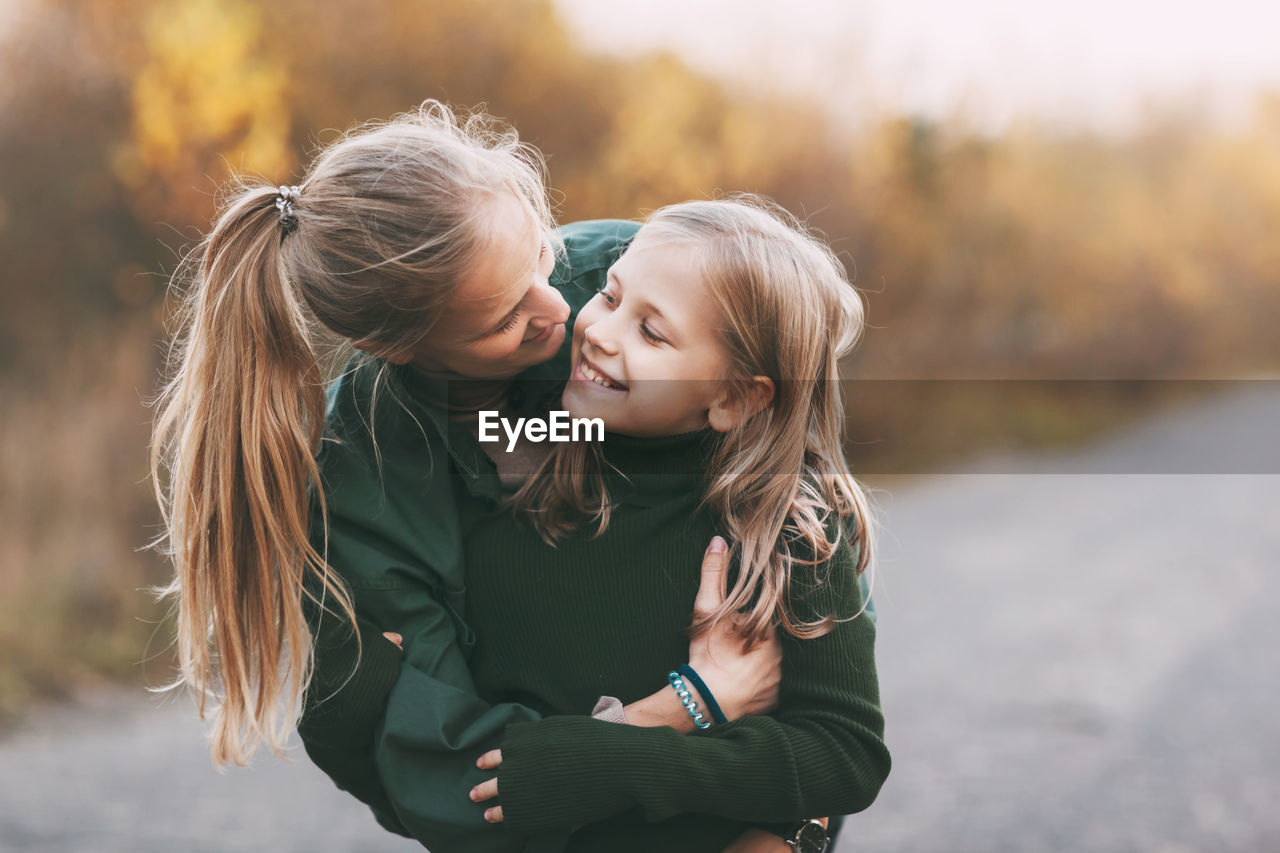 Portrait of happy mature mom and her blonde little daughter hugging and laughing