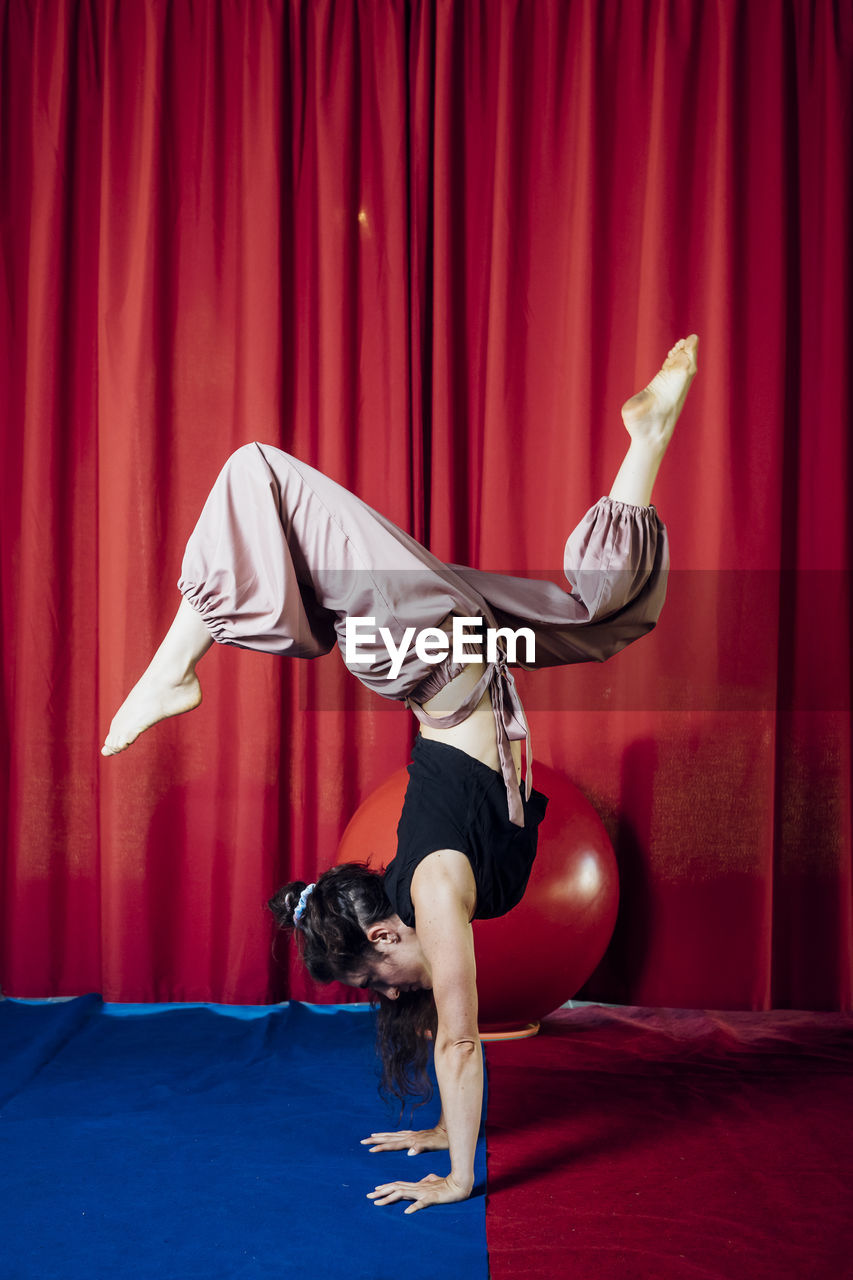 Female acrobat doing handstand on circus stage