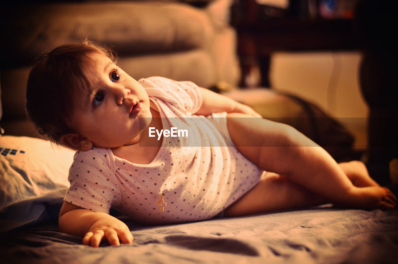 Portrait of cute baby lying on bed at home