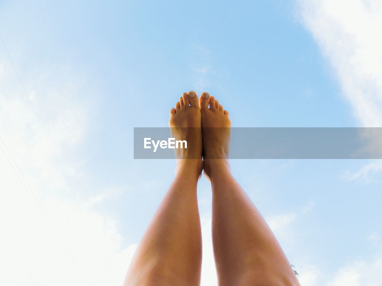 Low section of woman with feet up against sky