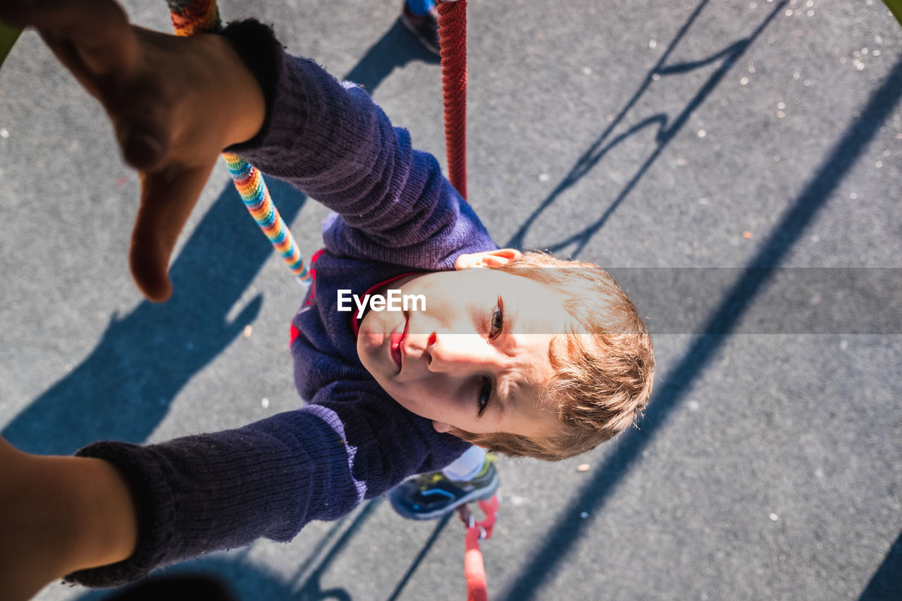 Directly above shot of boy hanging on rope at playground