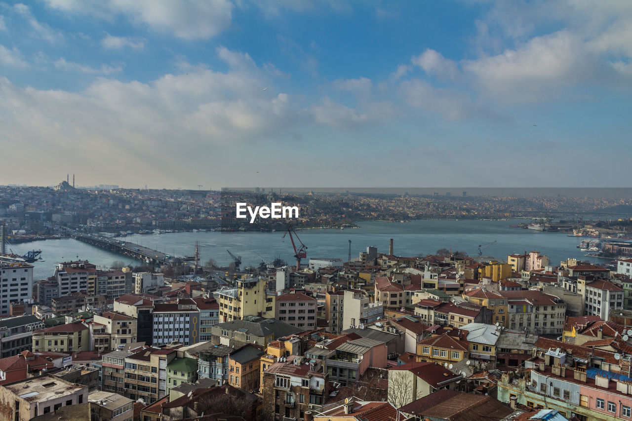 High angle view of city buildings against cloudy sky