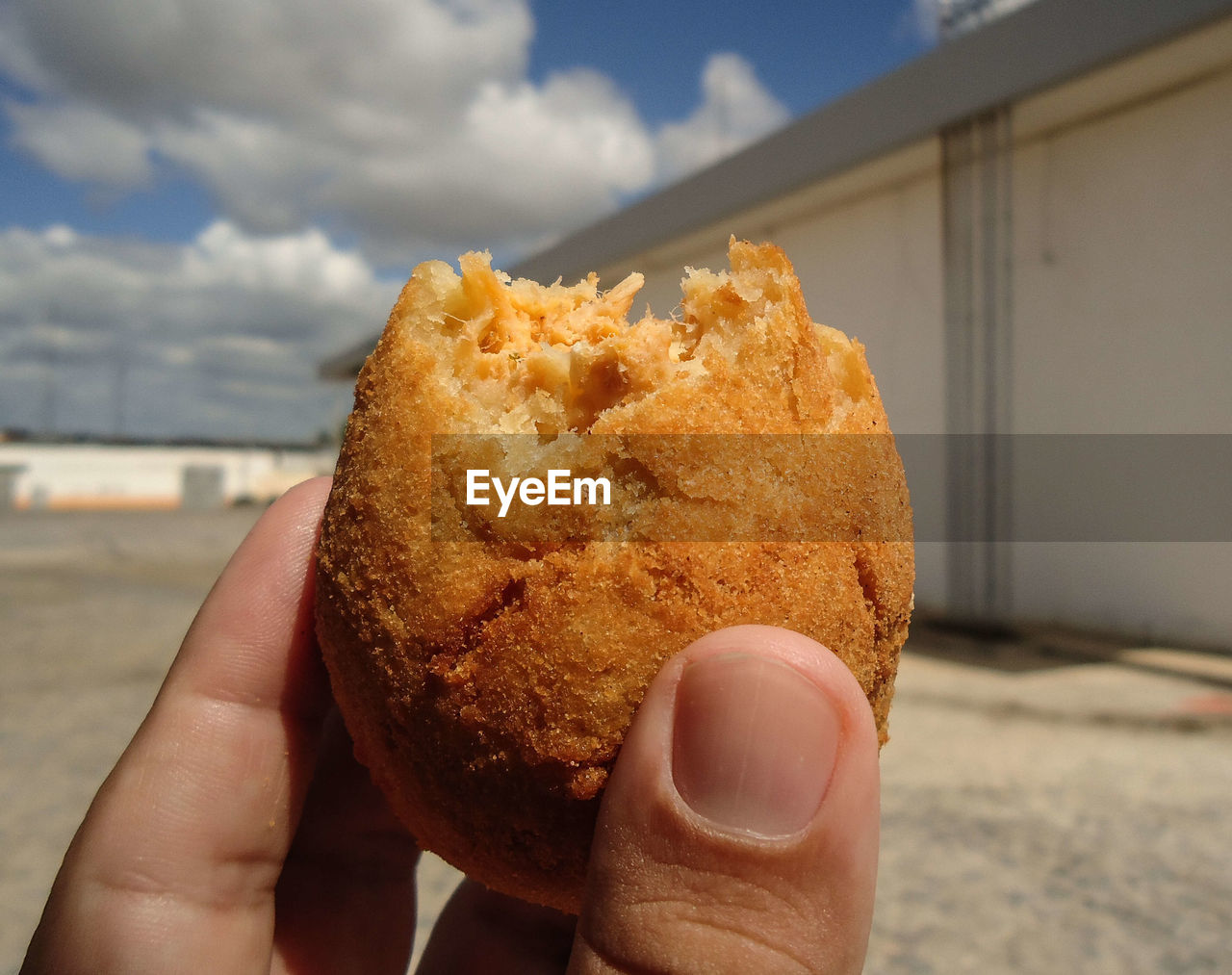 A hand holding a coxinha outdoors