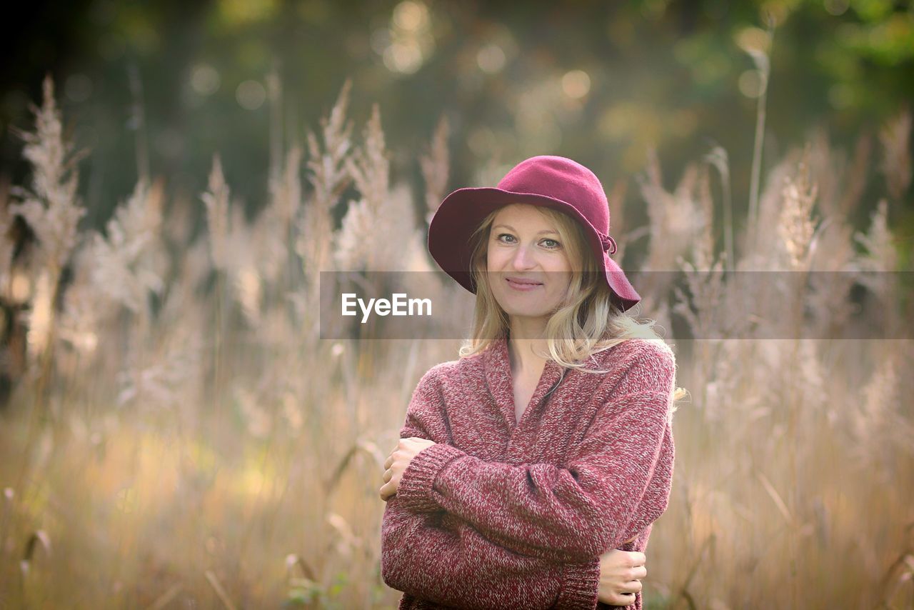 PORTRAIT OF BEAUTIFUL YOUNG WOMAN STANDING IN FIELD