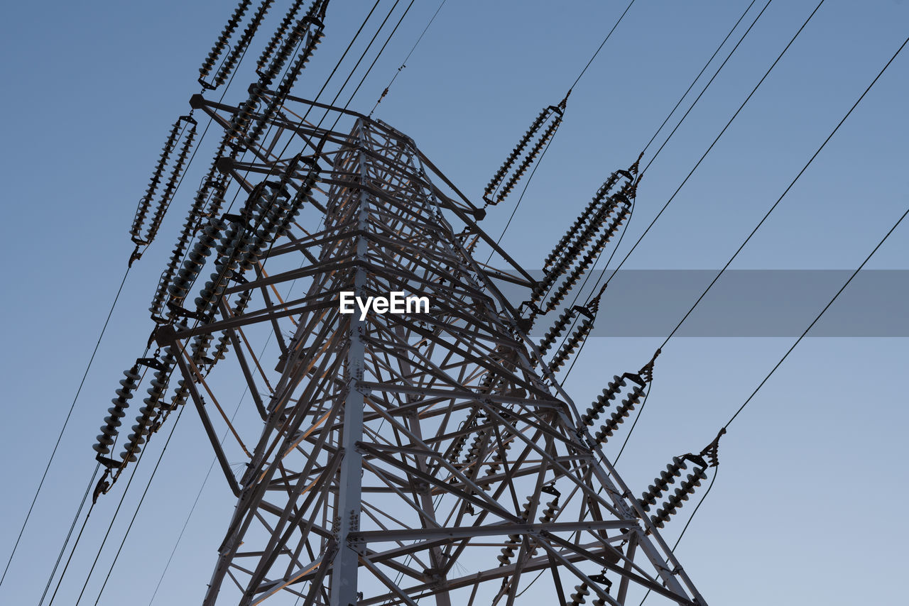 Low angle view of electricity pylon against clear blue sky