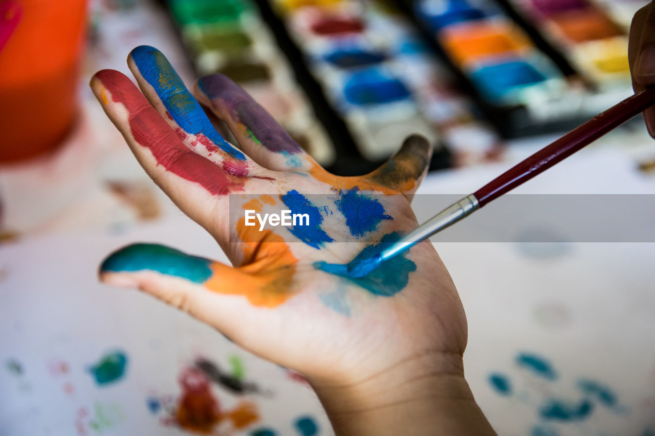 Cropped hands of child holding paintbrush