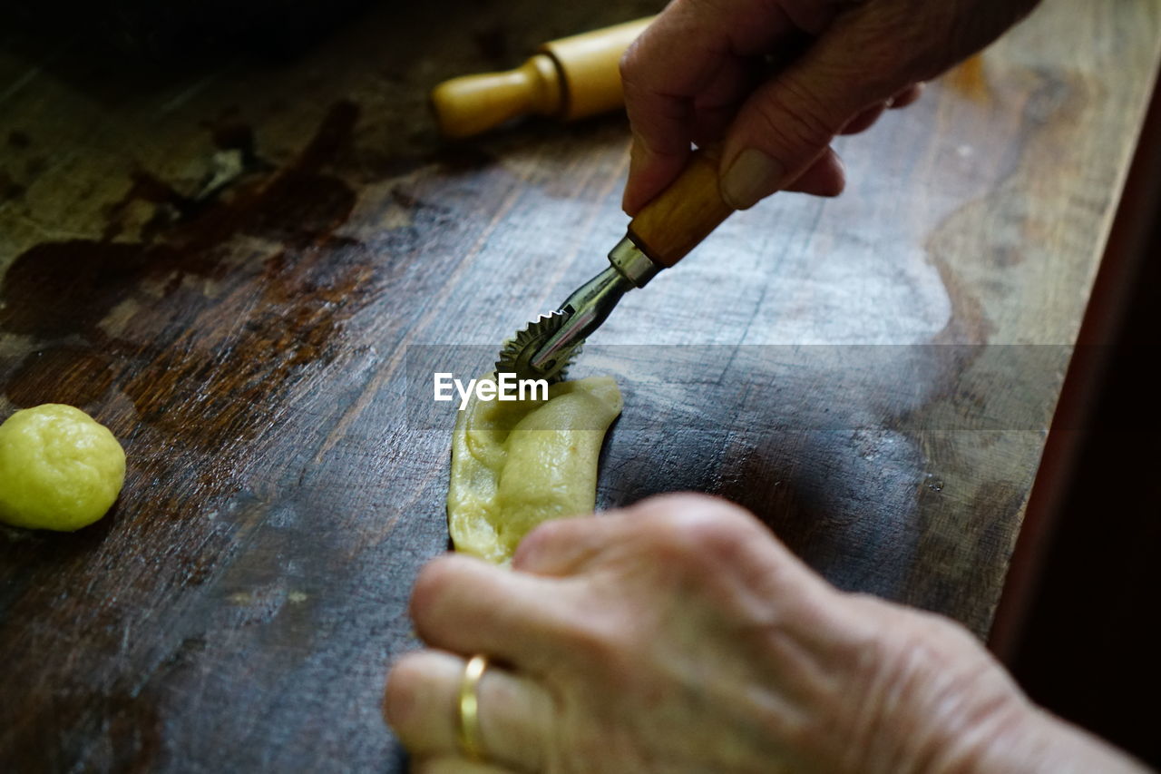 CLOSE-UP OF MAN PREPARING FOOD AT TABLE