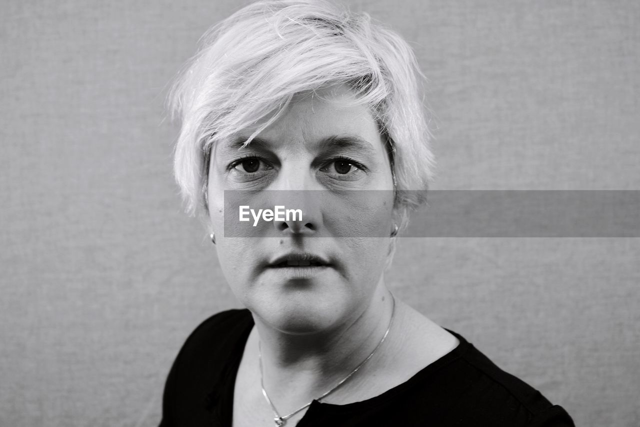 Portrait of woman with short hair against wall