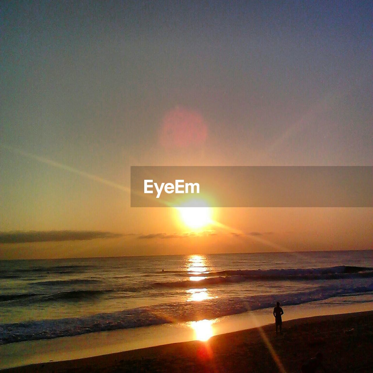 Silhouette man standing at beach against sky during sunset