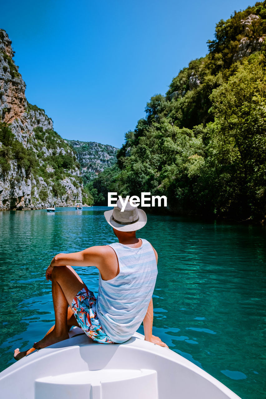 Rear view of man sitting on boat in lake