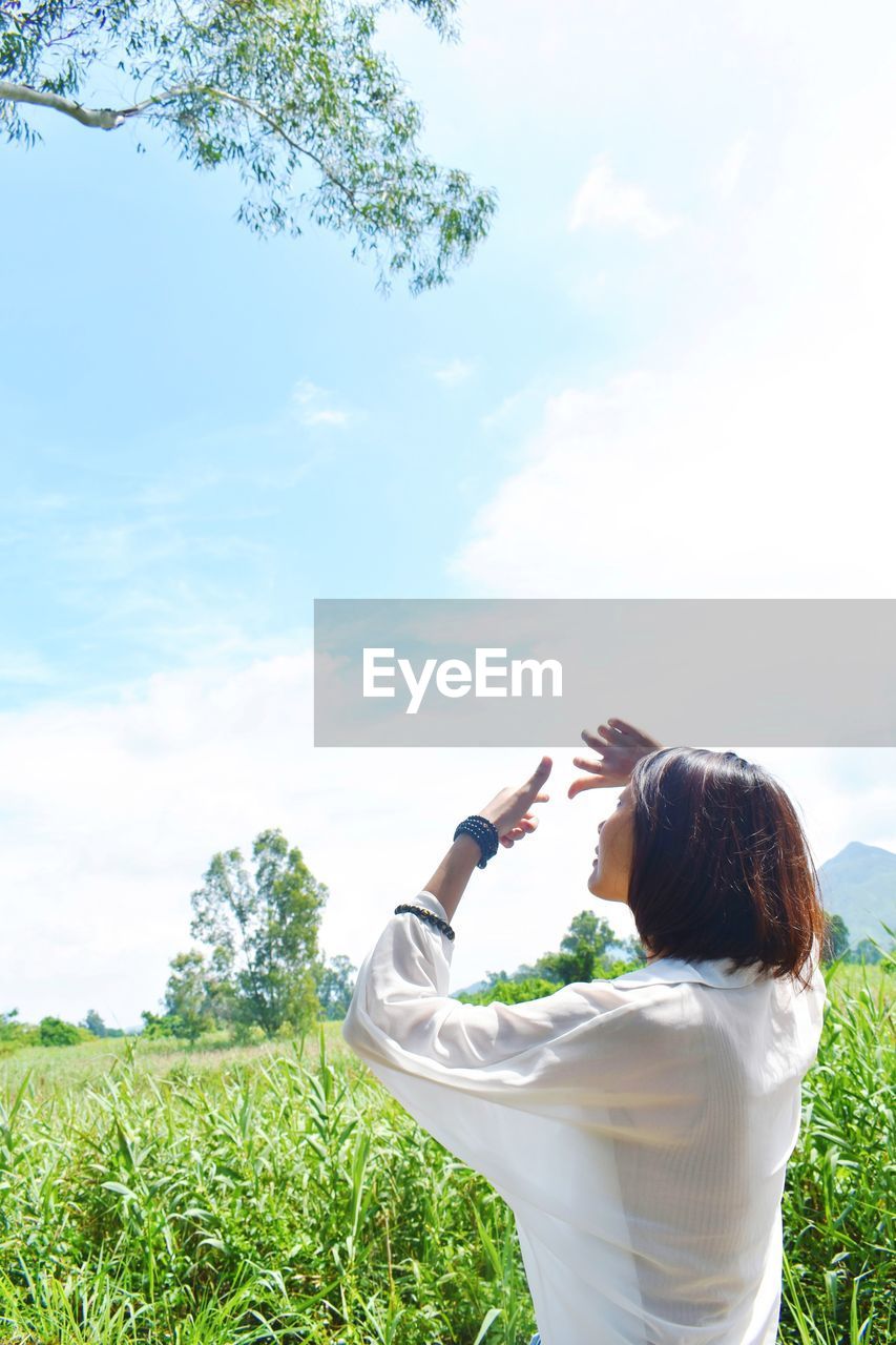 REAR VIEW OF WOMAN HOLDING UMBRELLA IN FIELD