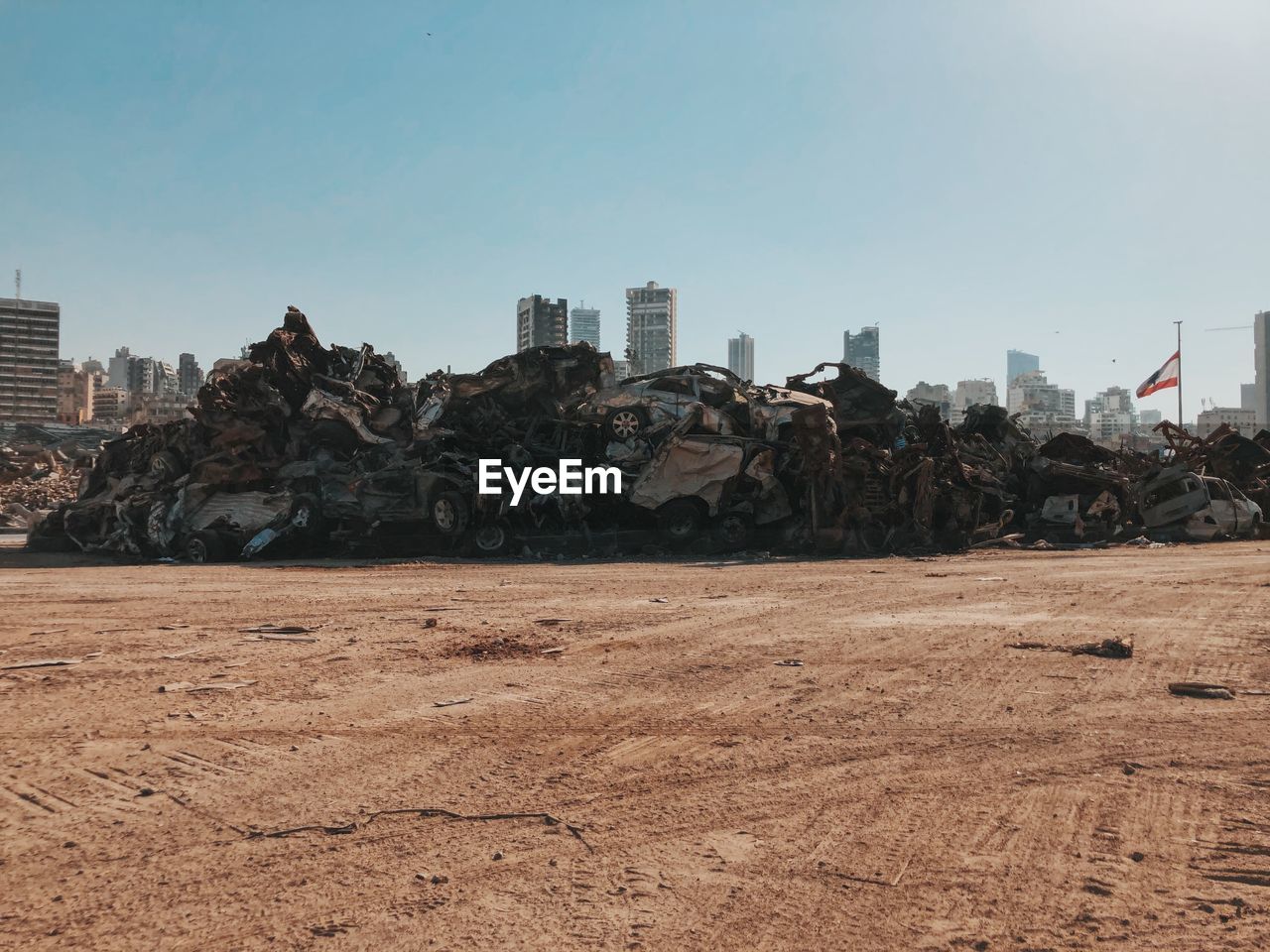 Stack of destroyed cars by buildings against sky