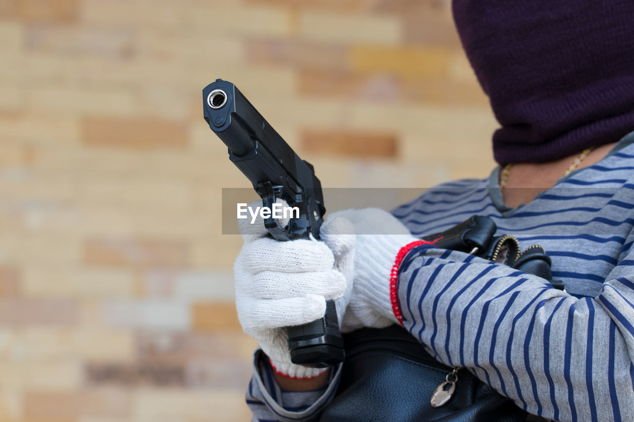 Midsection of man holding gun and purse