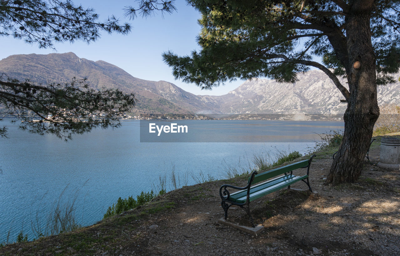 water, tree, plant, mountain, nature, scenics - nature, body of water, lake, beauty in nature, tranquility, bench, seat, tranquil scene, sky, wilderness, landscape, no people, environment, reservoir, reflection, land, day, outdoors, mountain range, beach, non-urban scene, travel destinations, lakeshore, idyllic, travel, tree trunk, trunk, relaxation, shore, tourism