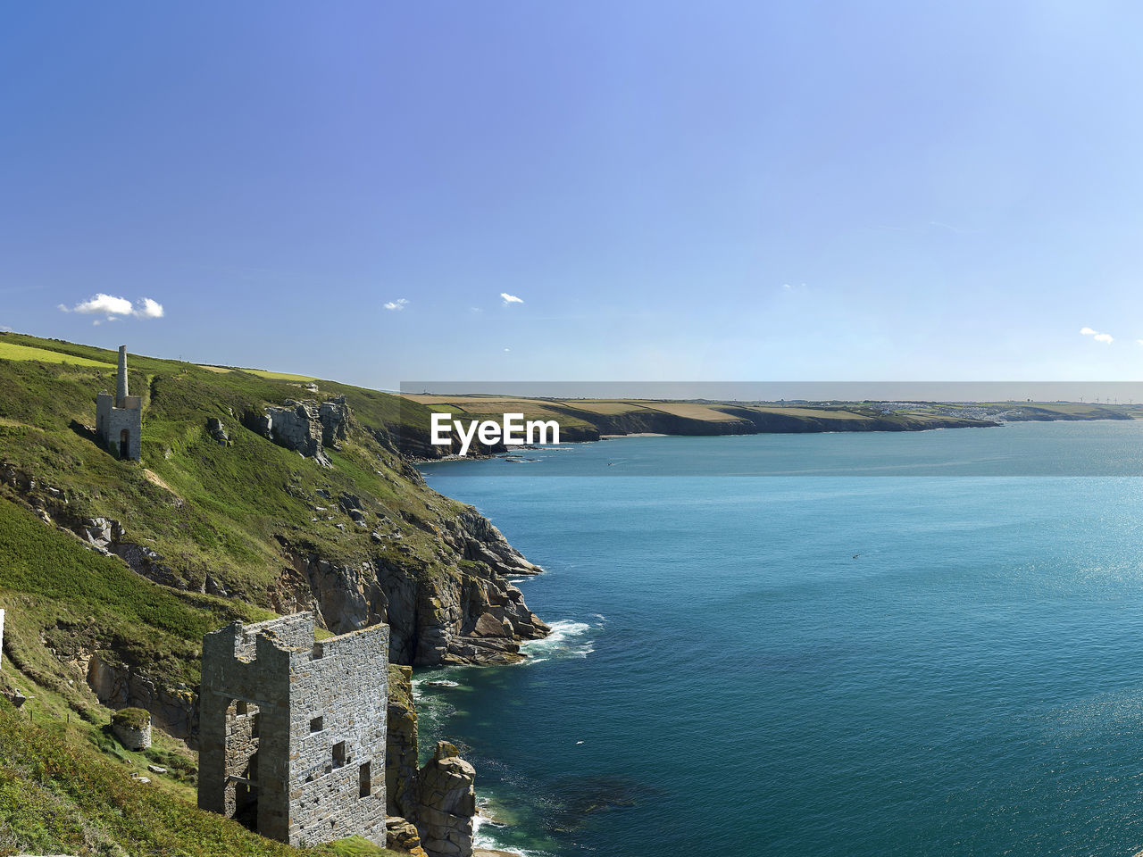 Scenic view of rocky coastline against blue sky