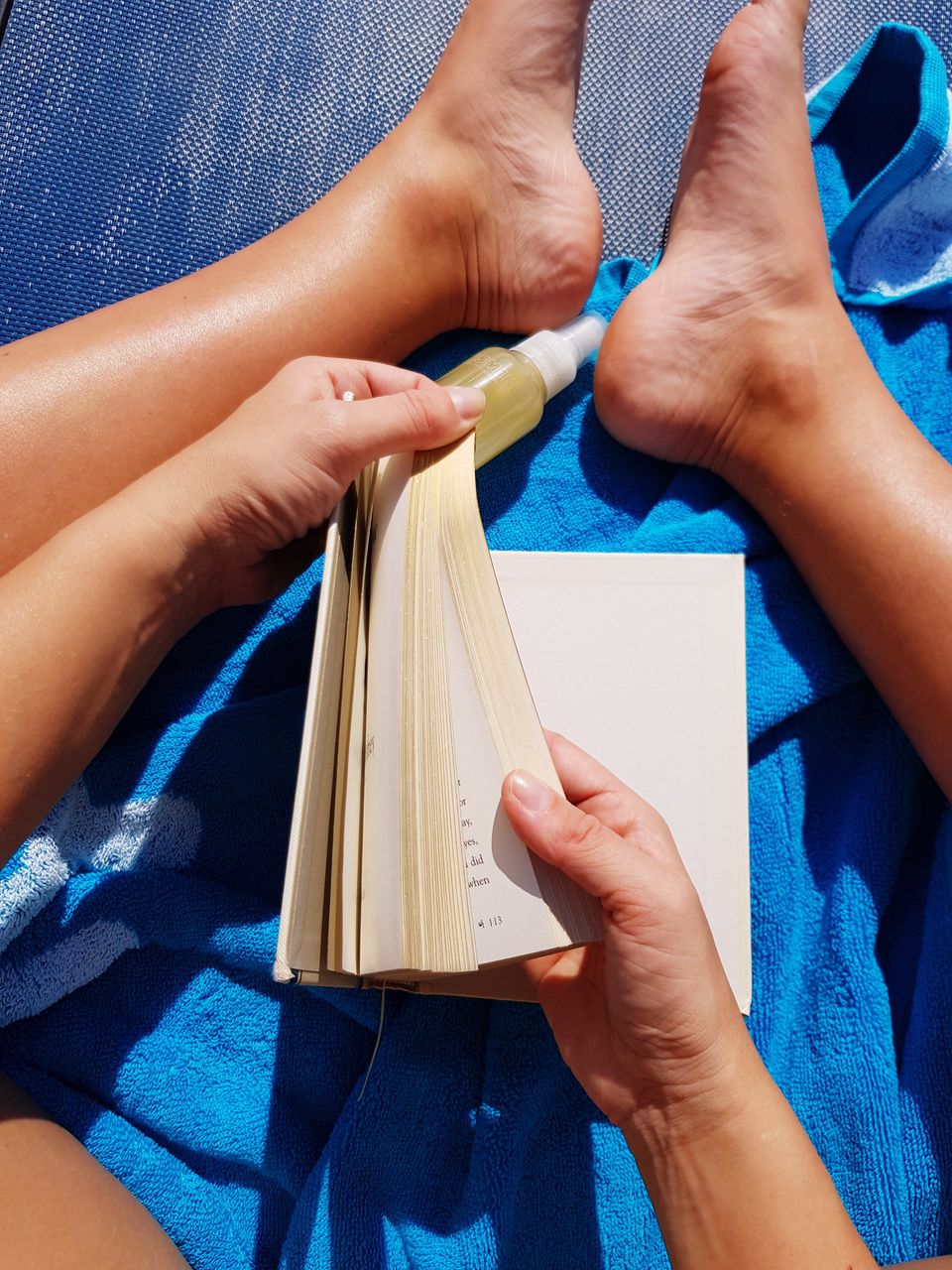 Low section of woman holding book on sunny day