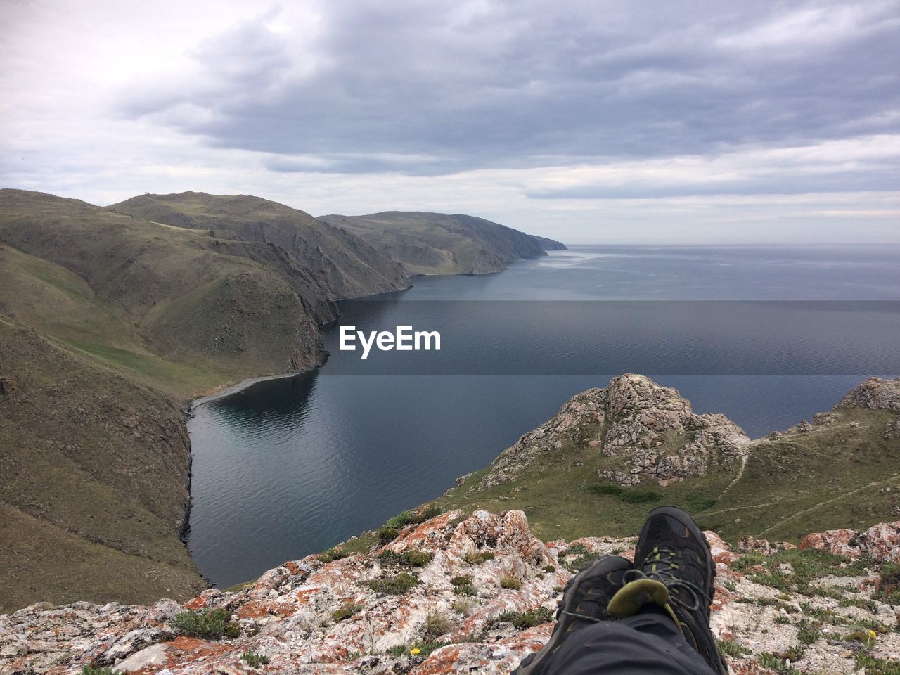 Low section of man on mountain at beach against sky