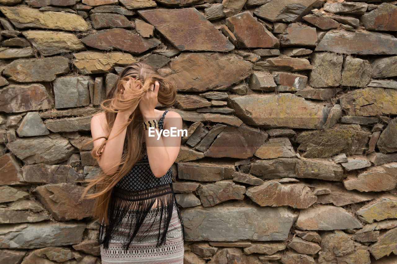 Woman standing by stone wall