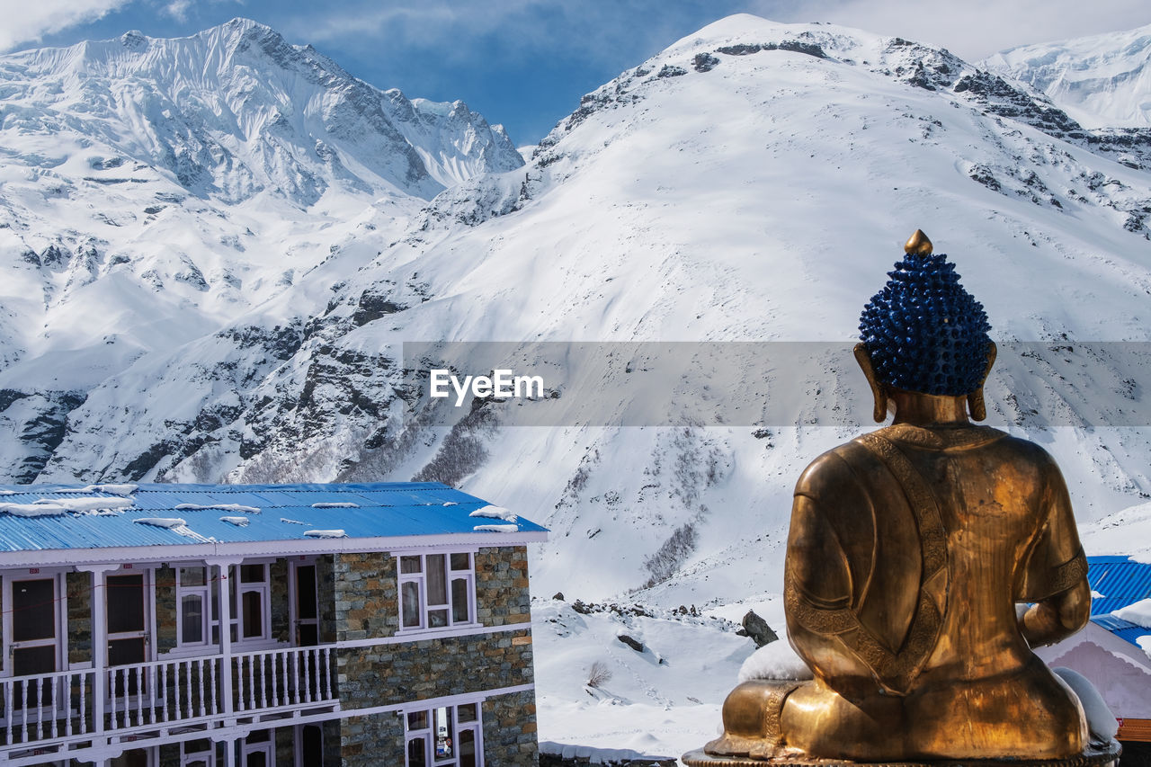 Buddha statue against snowcapped mountain