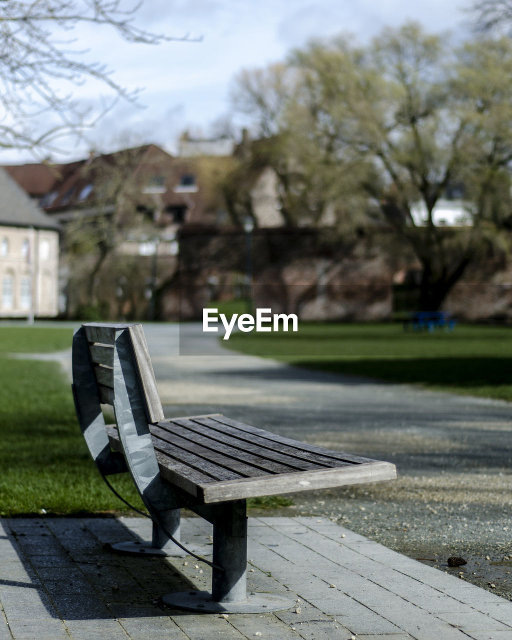 EMPTY BENCH IN PARK BY FOOTPATH