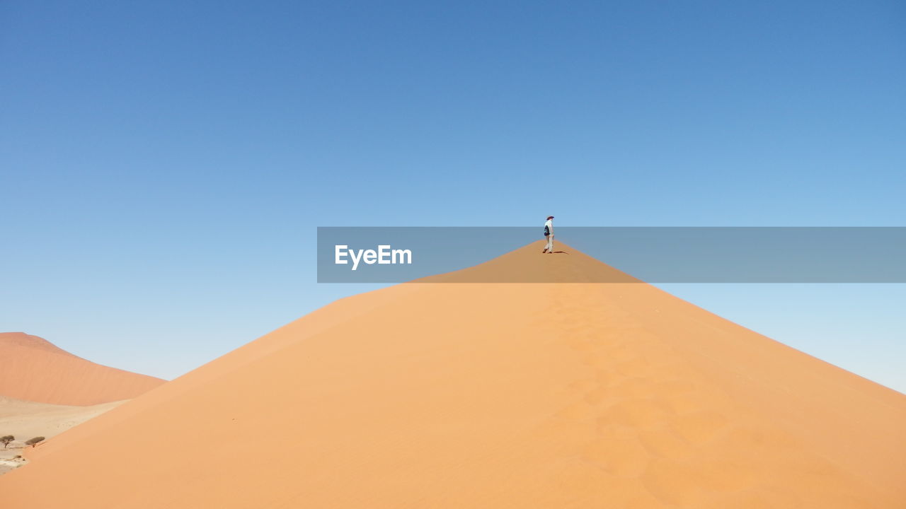 Low angle view of person standing on sand dune at namib desert